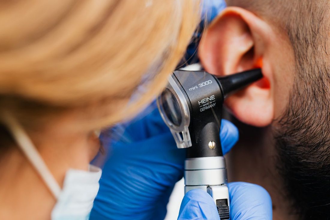Médico examinando o ouvido de um paciente com otoscópio